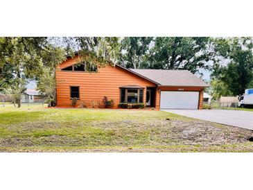 Charming two-story home features an attached garage, well-maintained lawn, and mature trees at 8504 N Campbell Rd, Lakeland, FL 33810