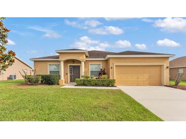 Charming single-story home with a well-manicured lawn and a two-car garage on a sunny day at 1975 Country Manor St, Bartow, FL 33830