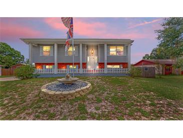 Charming two-story home featuring eye-catching architecture, a lovely fountain, and a well-maintained lawn at twilight at 2333 Cheshire Pl, Lakeland, FL 33810