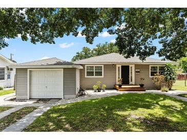 Charming single-story home with neutral siding, green lawn and complemented by mature trees overhead at 819 Glendale St, Lakeland, FL 33803