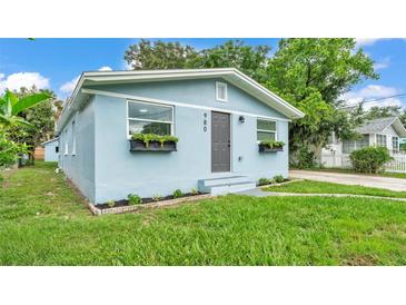 Charming blue home with a well-manicured lawn and flower boxes under the windows at 980 S Mill Ave, Bartow, FL 33830