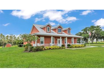 Charming one-story home featuring a metal roof, large front porch, and well-manicured lawn and landscape at 1044 Timbers Dr, Fort Meade, FL 33841