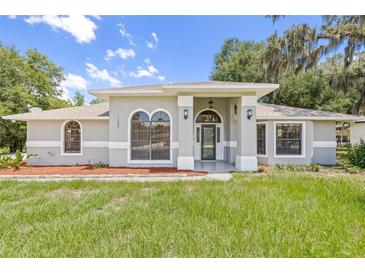 Charming home with a well-manicured lawn, arched windows, and a covered entryway at 1102 Berkley Ln, Winter Haven, FL 33880