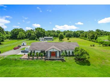 Aerial view captures a serene estate with a large house, a pond, green fields, and mature trees at 15195 Angus Rd, Polk City, FL 33868