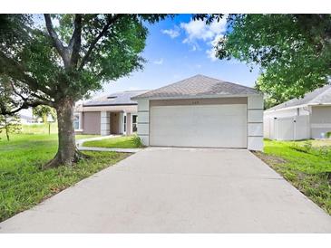 Charming single-story home with a two-car garage and solar panels on a sunny day at 169 Birmingham Dr, Kissimmee, FL 34758