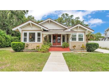 Charming bungalow with red front porch, walkway and well-manicured lawn under a partly cloudy blue sky at 236 E Seminole Ave, Lake Wales, FL 33853
