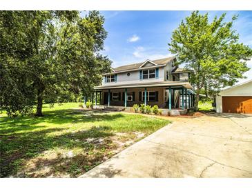 Charming two-story home with a covered front porch and mature trees in a lush green yard at 4510 Cindy Rd, Lakeland, FL 33810
