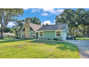 Charming single-story home with stone chimney, green siding, and mature trees at 6533 Angus Dr, Lakeland, FL 33810