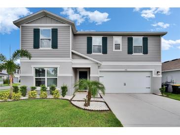 Charming two-story home featuring manicured landscaping, gray siding, dark green shutters, and an attached two-car garage at 7116 Cruz Ct, Lakeland, FL 33813