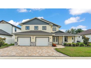 Charming two-story home featuring a three-car garage, a brick-paved driveway, and well-maintained landscaping at 2736 Sunrise Landing Ln, Lakeland, FL 33812