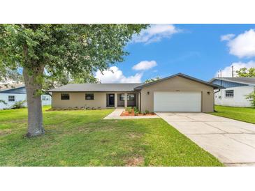Inviting single-story home featuring a well-manicured lawn, mature tree, and attached two-car garage at 4622 Grovecrest Dr, Lakeland, FL 33813
