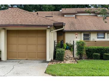 Charming townhome featuring a one-car garage, brick pathway, and manicured landscaping at 925 Fenton Ln # 18, Lakeland, FL 33809