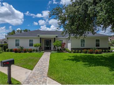 Charming single-story home featuring a landscaped yard with brick walkway at 128 Melissa Trl, Auburndale, FL 33823