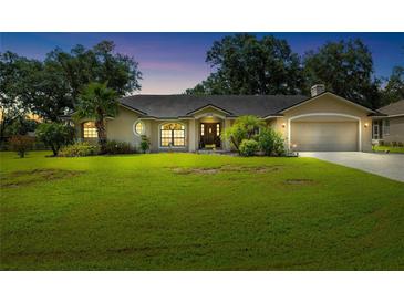 Charming single-story home with lush lawn, mature trees and inviting front entrance and attached two car garage at 2208 Deerbrook Dr, Lakeland, FL 33811