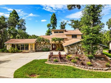 Charming home featuring a stone facade, mature landscaping, and a well-manicured lawn at 6033 Mountain Lake Dr, Lakeland, FL 33813