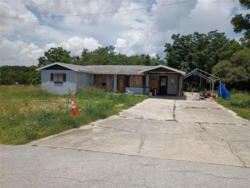 Exterior shot of property showing the house, overgrown yard, and driveway at 745 Drawdy Rd, Babson Park, FL 33827