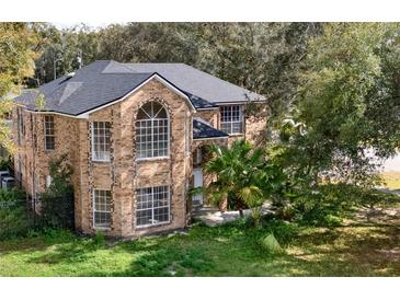 Charming two-story brick home featuring large windows, lush greenery, and a well-maintained front yard at 351 Crystal Ridge Way, Lake Mary, FL 32746