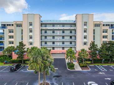 Coastal condominium building featuring a secured entrance, vibrant landscaping, and ample parking for residents and guests at 5300 S Atlantic Ave # 9-403, New Smyrna Beach, FL 32169