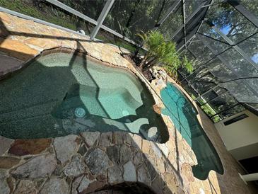 A unique, private pool and spa enclosed in screened enclosure, features rock accents, and lush landscaping at 1780 Otisco Way, Winter Springs, FL 32708