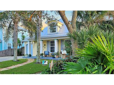 Charming yellow house with gray metal roof, front porch, and lush landscaping at 915 Maple St, New Smyrna Beach, FL 32169