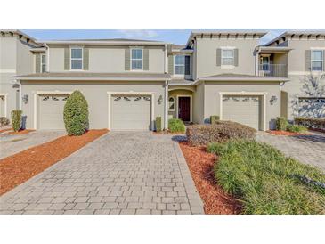 Tan three-story townhome with two-car garage and landscaping at 104 Kelly Thomas Way, Daytona Beach, FL 32124