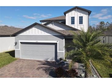 Two-story house with gray siding, gray roof, and a brick paver driveway at 3133 Crab Trap Dr, New Smyrna Beach, FL 32168