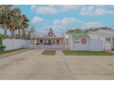 A charming two-story beach cottage with a white picket fence and a spacious yard at 321 Jessamine Ave, New Smyrna Beach, FL 32169