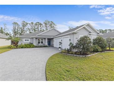 Gray house with three-car garage, paver driveway, and landscaped yard at 3309 Modena Way, New Smyrna Beach, FL 32168