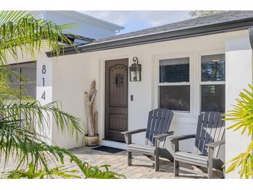 Inviting front entrance with a charming door, two adirondack chairs, and well-manicured landscaping at 814 E 20Th Ave, New Smyrna Beach, FL 32169