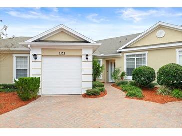 Tan colored villa with white garage door and landscaped walkway at 121 Sedona Cir, Daytona Beach, FL 32124