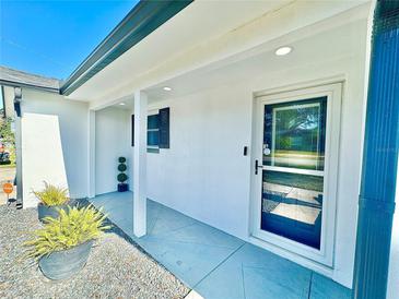 Inviting front entrance with a storm door, gray patio, and a modern white exterior at 2101 Oriole Ln, South Daytona, FL 32119