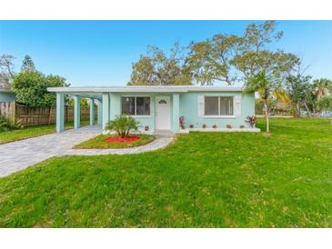 Charming light teal home with landscaped lawn and a paved walkway at 211 Maurice Ave, New Smyrna Beach, FL 32168