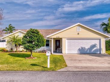 Cute yellow house with a white garage door and manicured lawn at 216 Fairgreen Ave, New Smyrna Beach, FL 32168