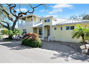 Two-story yellow house with white trim, balcony, and paver driveway at 221 Columbus Ave, New Smyrna Beach, FL 32169