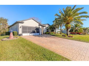 Single-story home with paver driveway, screened garage, and lush landscaping at 258 Navajo Dr, Oak Hill, FL 32759