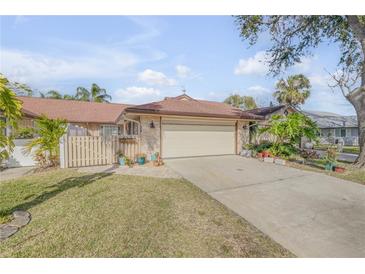 Front view of charming house with attached garage, manicured lawn, and mature landscaping at 28 Lake Fairgreen Cir, New Smyrna Beach, FL 32168