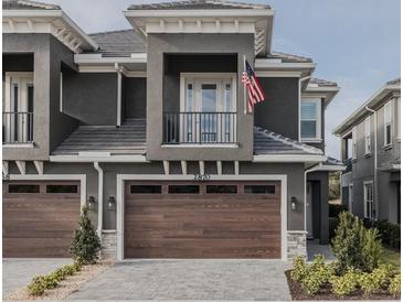 Two-story townhome with dark gray exterior, brown garage doors, and small balcony at 2870 Isles Way, New Smyrna Beach, FL 32168