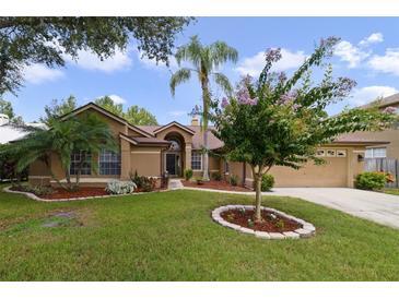 Tan house with landscaped yard, palm tree, and two-car garage at 3084 Heartleaf Pl, Winter Park, FL 32792