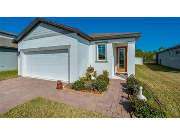 Single-story home with a white exterior, two-car garage, and landscaped front yard at 3191 Crab Trap Dr, New Smyrna Beach, FL 32168