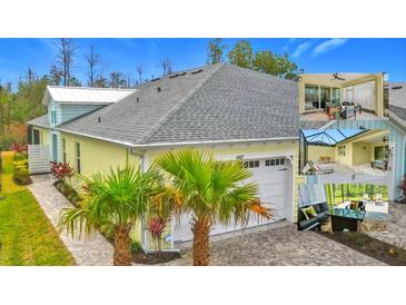 Bright yellow house with gray roof, white garage door, and palm trees in the front at 667 Margaritaville Ave, Daytona Beach, FL 32124