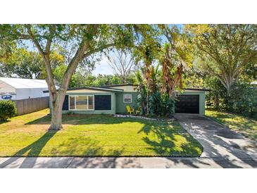 Ranch style home with a green exterior, black garage door, and nicely landscaped lawn at 729 N Flamingo Dr, Daytona Beach, FL 32117