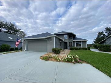 Gray house with attached garage, stone walkway, and landscaped lawn at 1104 Red Maple Way, New Smyrna Beach, FL 32168