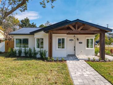 Charming single story home with stucco facade, dark metal roof and attractive walkway to a covered entry at 1423 Palmetto St, New Smyrna Beach, FL 32168