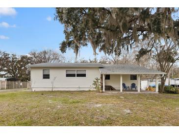 Ranch style home with covered porch and large oak tree at 1596 Elizabeth St, New Smyrna Beach, FL 32168