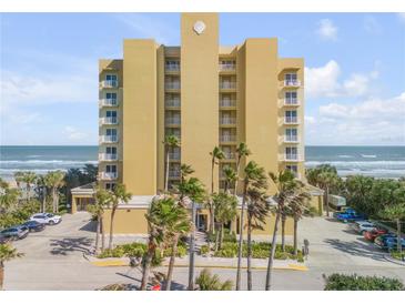 Oceanfront building, featuring a light yellow facade and ample parking at 1705 S Atlantic Ave # 302, New Smyrna Beach, FL 32169