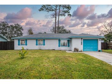 White brick ranch house with teal accents, a blue garage door, and a well-maintained lawn at 2325 Willow Oak Dr, Edgewater, FL 32141