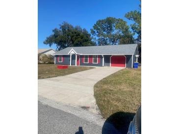 Ranch-style home with gray siding, red accents, and a two-car garage at 2723 Juniper Dr, Edgewater, FL 32141