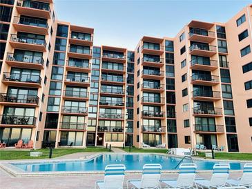 Exterior view of building with pool, lounge chairs, and ocean view at 4141 S Atlantic Ave # 602, New Smyrna Beach, FL 32169