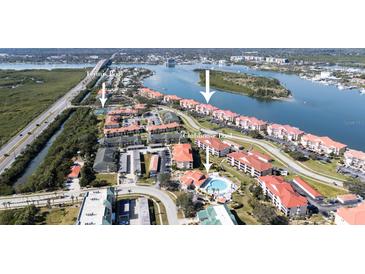 Aerial view of community featuring tennis court, pool, and waterfront condos with boat docks at 456 Bouchelle Dr # 202, New Smyrna Beach, FL 32169