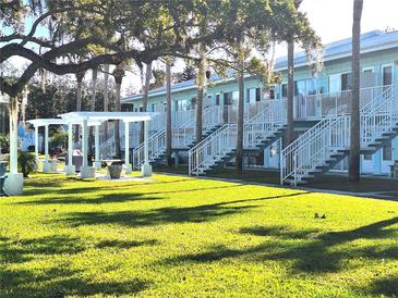 Light teal building with multiple units, stairs, and a grassy courtyard at 541 S Peninsula Ave # A03, New Smyrna Beach, FL 32169